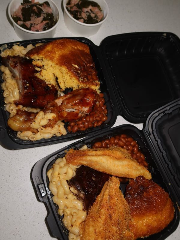 Plates of ribs, chicken, fried catfish, mac and cheese, beans, and cornbread