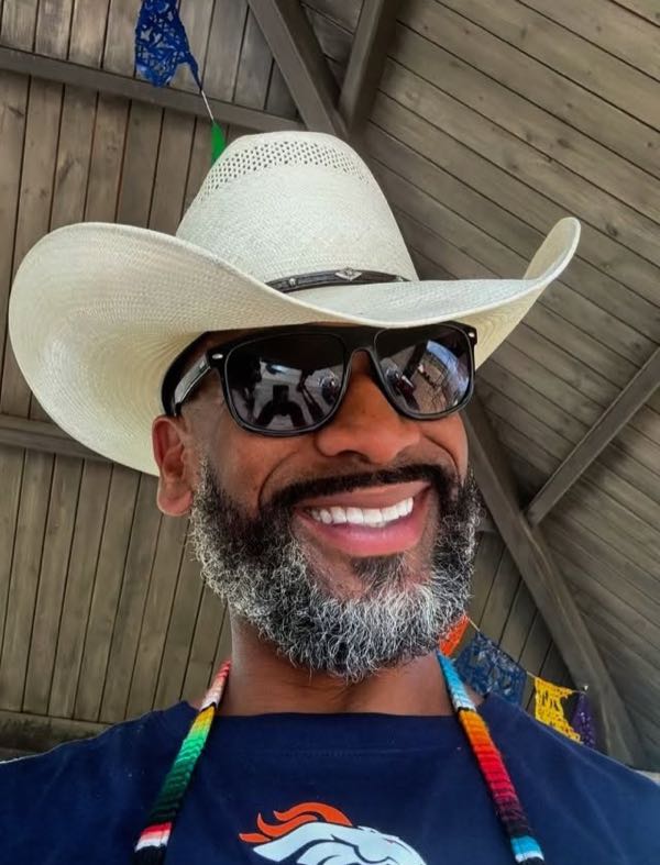 Robert Manlove smiling in a cowboy hat and sunglasses